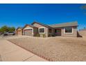 Single-story tan home with two car garage and gravel yard at 4542 N 86Th Dr, Phoenix, AZ 85037