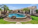 Inviting backyard pool with rock features, palm trees, patio, and covered seating area perfect for relaxation at 5046 W Monte Cristo Ave, Glendale, AZ 85306
