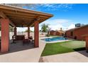 Inviting backyard featuring a covered patio, swimming pool, and putting green, perfect for entertaining at 654 W Plata Ave, Mesa, AZ 85210