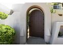 Close-up of a dark wood gate framed by curved stucco walls and greenery leading to the courtyard at 10795 E Sutherland Way, Scottsdale, AZ 85262