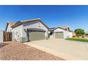 Exterior view of the home, showing the two-car garage, desert landscaping, and side gate at 13628 W San Miguel Ave, Litchfield Park, AZ 85340