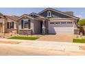 Charming single-story home featuring a two-car garage, stone accents, and a well-maintained lawn at 15784 W Georgia W Dr, Surprise, AZ 85379