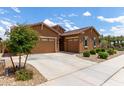 Attractive single-story home featuring a three-car garage, desert landscaping, and a charming stone accent at 24327 N 163Rd Dr, Surprise, AZ 85387