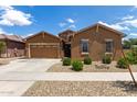 Charming single-story home features a two-car garage, manicured desert landscaping, and a stone front accent at 24327 N 163Rd Dr, Surprise, AZ 85387