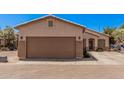 Home with a brown two-car garage and desert landscaping under a blue sky in a well-maintained community at 2635 E Riviera Dr, Chandler, AZ 85249