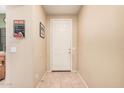 Hallway with beige walls and tile flooring, leading to a white door and a Coca-Cola themed decoration at 2635 E Riviera Dr, Chandler, AZ 85249