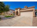 Beige stucco home with a large garage door and arched entryway, showcasing the well-maintained front yard at 800 W Sycamore Ct, Litchfield Park, AZ 85340