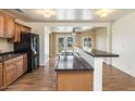 Open kitchen with wood floors features wooden cabinets, black appliances, and a breakfast bar at 1836 W Las Palmaritas Dr, Phoenix, AZ 85021