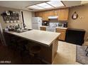The kitchen features oak cabinets, a large island with breakfast bar and white appliances at 3535 W Monte Cristo Ave # 129, Phoenix, AZ 85053