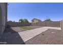 Spacious backyard featuring a brick-paved patio, low maintenance desert landscaping, and a decorative patch of turf at 41388 W Hopper Dr, Maricopa, AZ 85138