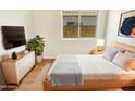 Bright bedroom featuring a modern dresser, television, decor, and natural light from a window at 4626 E Villa Rita Dr, Phoenix, AZ 85032