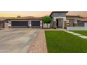 Charming single-story home featuring a well-manicured lawn, three-car garage, and neutral-toned facade with decorative stone accents at 4706 E Des Moines St, Mesa, AZ 85205