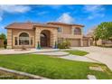 Inviting home exterior with lush green lawn, mature trees, and a circular driveway leading to a spacious three-car garage at 5510 N 132Nd Dr, Litchfield Park, AZ 85340