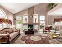 Bright living room with vaulted ceilings, large windows, ornate fireplace, and comfortable seating; perfect for relaxation at 5510 N 132Nd Dr, Litchfield Park, AZ 85340