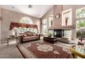 Spacious living room featuring vaulted ceilings, expansive windows, cozy seating, and an elegant fireplace with decorative accents at 5510 N 132Nd Dr, Litchfield Park, AZ 85340