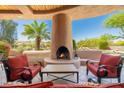 Covered outdoor patio featuring a cozy fireplace and comfortable seating, perfect for enjoying desert views at 10901 E Quarry E Trl, Scottsdale, AZ 85262