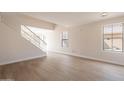 Bright living room with laminate floors, large windows, and staircase with white banister at 13706 N 130Th Ave, El Mirage, AZ 85335