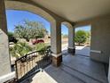 Arched porch with iron railing shows desert landscaping, a red car, and a tree at 17477 W Woodrow Ln, Surprise, AZ 85388