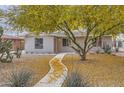 Single-story home with desert landscaping, including mature trees and native cacti at 2021 W Clarendon Ave, Phoenix, AZ 85015