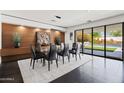 Open dining room features dark tile floors, a glass table, and access to outdoor living at 3710 E Hazelwood St, Phoenix, AZ 85018