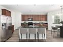 Bright kitchen features dark cabinets, stainless steel appliances, an island and bar stool seating at 4149 E Devon Dr, Gilbert, AZ 85296