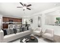Open-concept living room featuring white walls, modern furniture, ceiling fan, and views of the kitchen and dining area at 4149 E Devon Dr, Gilbert, AZ 85296