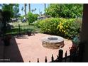 Relaxing outdoor patio with a cozy stone fire pit, brick pavers, and a wrought iron fence at 717 E State Ave, Phoenix, AZ 85020
