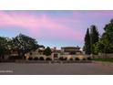 Luxurious estate showcasing grand architecture, lush landscaping, and gated entry at dusk with colorful skies at 7525 N Shadow Mountain Rd, Paradise Valley, AZ 85253