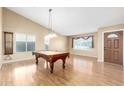 Spacious living room featuring hardwood floors and an elegant pool table with a chandelier at 7966 W Surrey Ave, Peoria, AZ 85381