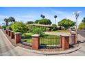 Street view of a beautiful home with lush landscaping, a brick fence, and mature palm trees at 1941 E Hazelwood St, Phoenix, AZ 85016