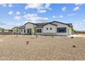 A contemporary one-story home with a gravel yard, green grass and desert plants provides low maintenance landscaping at 3933 E Freeman Ln, San Tan Valley, AZ 85140