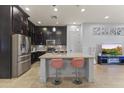 Modern kitchen features stainless steel appliances, dark cabinets, an island, and bar seating at 6565 E Thomas Rd # 1128, Scottsdale, AZ 85251
