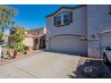 Townhome featuring a two-car garage, long driveway, and desert landscaping at 8854 W Aster Dr, Peoria, AZ 85381