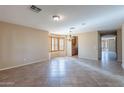 Bright, open-concept living space with tiled flooring, neutral walls, and elegant chandelier at 10517 W La Reata Ave, Avondale, AZ 85392