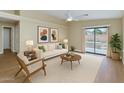 Bright living room featuring a ceiling fan, light-colored sofa, and a large sliding door at 12450 W Hearn Rd, El Mirage, AZ 85335