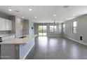 Open living area with wood-style tile flooring, modern lighting, and sliding glass doors to the backyard at 16551 W Desert Ln, Goodyear, AZ 85338