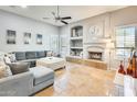 An open-concept living room with stone floors, a ceiling fan, and a decorative fireplace at 20608 N 57Th Ave, Glendale, AZ 85308