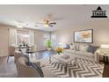 Bright, staged living room featuring stylish furniture, neutral walls, and a ceiling fan with direct access to a dining area at 22320 W Morning Glory St, Buckeye, AZ 85326