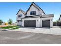 Modern two-story home featuring white brick, dark accents, and a spacious driveway leading to attached garages at 26619 S 169Th Pl, Queen Creek, AZ 85142