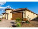 Side view of home, featuring a clay roof, desert landscaping and large two-car garage at 27021 W Kerry Ln, Buckeye, AZ 85396
