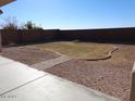 A simple backyard with gravel and a small patch of grass surrounded by a concrete border at 29797 W Mitchell Ave, Buckeye, AZ 85396