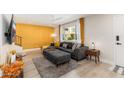 Bright living room showcasing stylish gray sofa, textured gold wall, and large window with bright natural light at 6957 E Osborn Rd # A, Scottsdale, AZ 85251