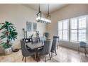 Formal dining room with modern chandelier, neutral paint, and large windows with shutter blinds at 8024 W Vista Ave, Glendale, AZ 85303