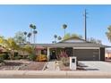 Charming single-story home with desert landscaping, palm trees, and a modern dark gray two-car garage at 8730 E Montecito Ave, Scottsdale, AZ 85251