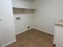 Functional laundry room features a shelf, electric outlets, and neutral tile flooring at 9556 W Blue Sky Dr, Peoria, AZ 85383