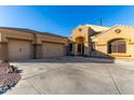 Charming exterior view of the single-Gathering home featuring a desert landscape and a three-car garage at 10040 E Grandview St, Mesa, AZ 85207