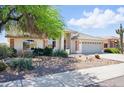 Well-maintained single-story home showcasing manicured landscaping, desert accents, and an attached garage at 11059 E Kilarea Ave, Mesa, AZ 85209