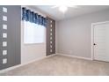 Neutral bedroom featuring a window with stylish valance, gray accent wall, carpet, and ceiling fan at 12547 W Stella Ln, Litchfield Park, AZ 85340