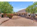 Expansive backyard featuring a brick patio, seating area, mature trees, and outdoor grill, perfect for entertaining at 12630 W Corrine Dr, El Mirage, AZ 85335