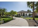 Stunning single-story home featuring arched windows, stone accents, and a circular driveway surrounded by palm trees at 12820 N 83Rd Pl, Scottsdale, AZ 85260